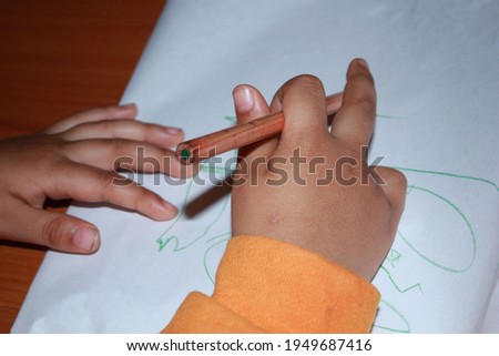 A 3-year-old boy holding a pencil in his hand.