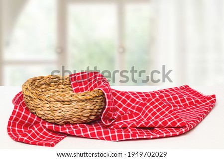 Empty picnic basket. Close-up of a empty straw basket and red napkin on table over blurred windows background. For food and product display montage. Macro.