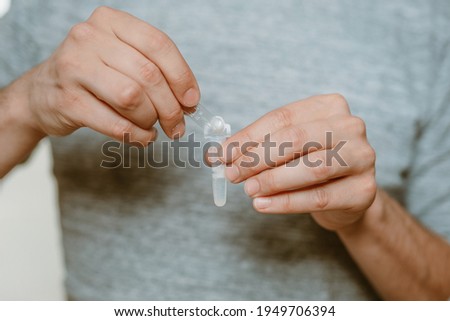 Lateral-Flow-Test covid rapid home-use test kit for saliva - step 2 - fill in testing liquid of ampoule in plastic tube Royalty-Free Stock Photo #1949706394