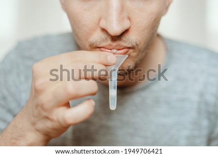 Lateral-Flow-Test covid rapid home-use test kit for saliva - step 1 - spit with mouth through funnel in plastic tube to collect sample - No more swabs in the throat or nose: just spit in a tube! Royalty-Free Stock Photo #1949706421