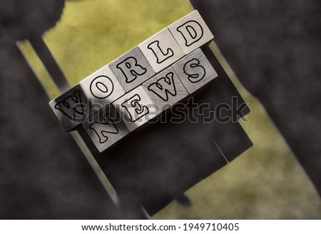 The inscription on the white cubes - world news on a gray-yellow background with shadows.