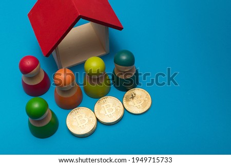 Golden bitcoins with decorations (colorful wooden peg dolls and wooden house), on blue background. Selective focus photo of bitcoins.