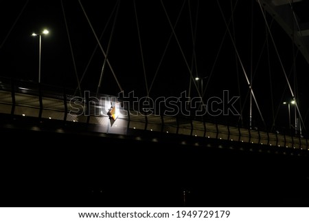 Nautical traffic sign for ships illuminated by a spotlight on the bridge over the river during the night