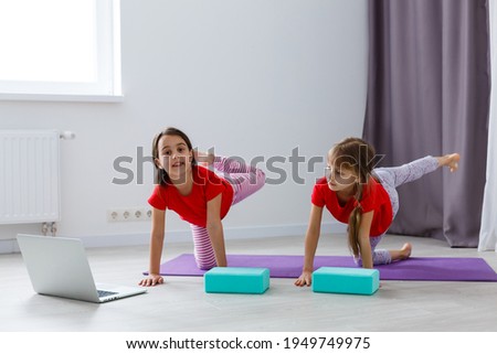 Beautiful athletic young girls practicing yoga together at home