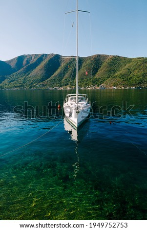 White yacht moored to the shore of the Bay of Kotor in the town of Perast.