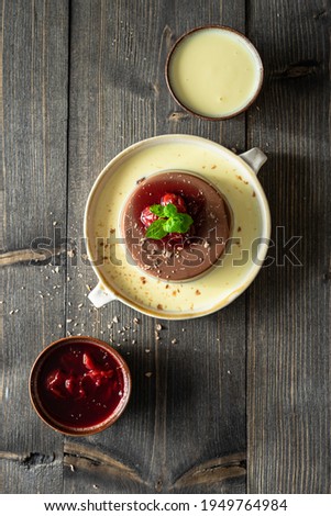 Homemade chocolate pudding served with vanilla sauce, mint and cherries