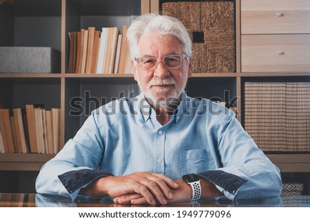 Portrait of one old cheerful male senior smiling having fun at home. Mature caucasian man studying independent looking at the camera and posing to picture.