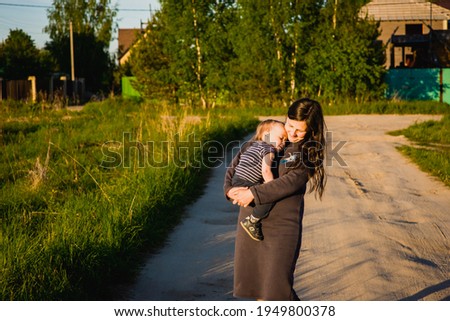 little boy walks with mom outdoors at sunset