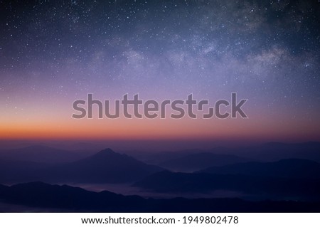 Beautiful picture of the night sky seen from the mountain peak, overlapping mountains, sea of mist, constellations and the Milky Way.