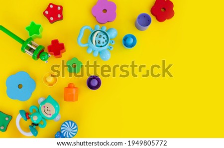 a variety of multi-colored children's toys on a yellow background. copy space