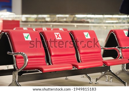 Several rows of empty red leather seats inside lounge of contemporary airport where you can sit, relax or take a nap while waiting for flight