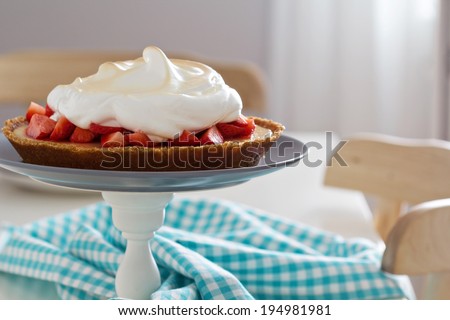 Lemon strawberry meringue pie on a cake stand