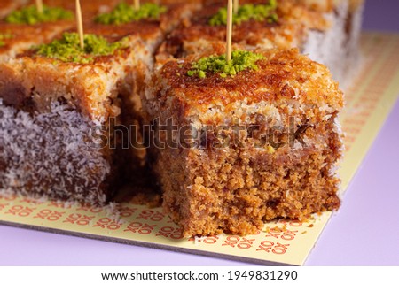 coconut date cake with pistachio in the top on purple background 