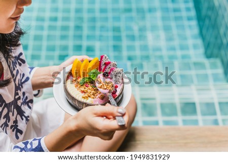 Woman having smoothie breakfast by swimming pool