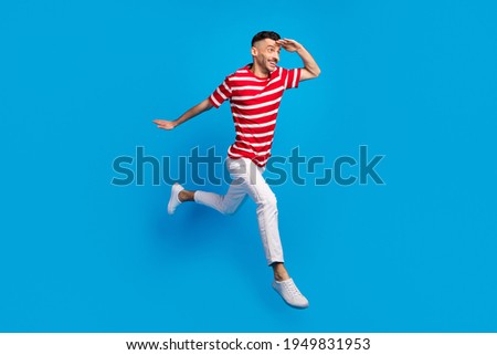 Full size profile side photo of handsome brunette man look froward copyspace run jump isolated on blue color background