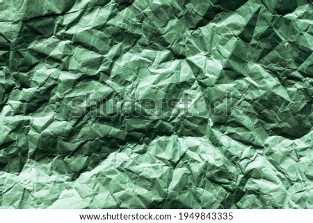 green crumpled paper texture background. shadows and huts resemble the surface of an unknown planet, a picture from space