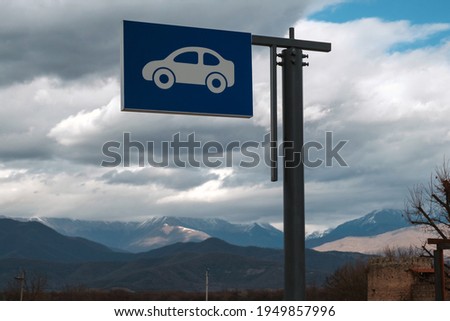 Outdoor car parking sign with mountains and cloudy sky background