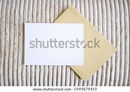 Greeting card, postcard, invitation with envelope mock up on cozy apparel background in interior. Flat lay.