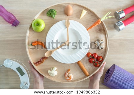 Intermittent fasting IF diet concept with 16:8 hour clock timer for skipping meal and eating keto low carb, high fat food meal healthy nutritional dish with gym exercise for body weight loss Royalty-Free Stock Photo #1949886352