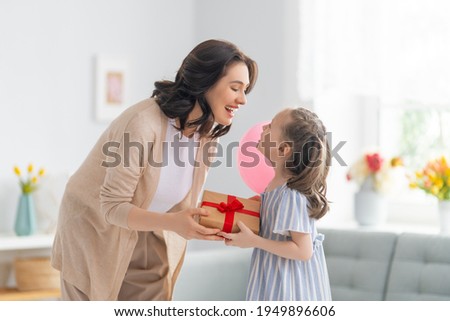 Happy mother's day! Child congratulating mom. Mum and daughter smiling and holding gift. Family holiday and togetherness.