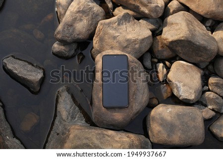 Smartphone on pebbles and water