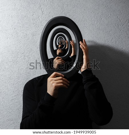 Enigmatic surrealistic optical illusion, young man holding round frame on textured grey background. Contemporary artwork collage concept. Royalty-Free Stock Photo #1949939005