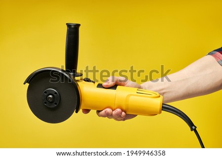 modern working tool, hand-held, yellow electric circular wood saw, bulgarian, angle grinder isolated on yellow