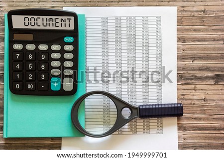 A calculator labeled DOCUMENT lies on financial documents in the office. Business concept.