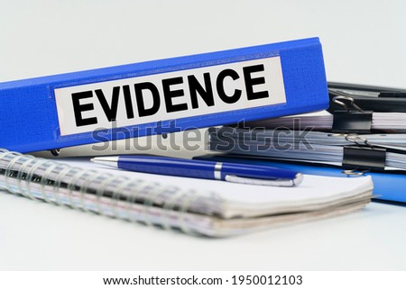 Business and finance concept. On the table are a notebook, a pen, documents and a folder with the inscription - EVIDENCE Royalty-Free Stock Photo #1950012103