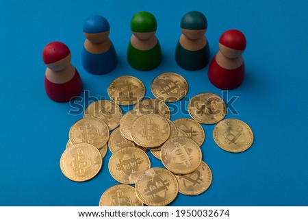 Golden bitcoins with colorful wooden peg dolls, on blue background. A selective focus photo of bitcoins. A crypto currency investment concept.