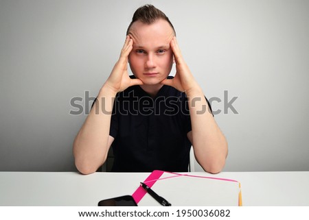 Tired stressful man keeps hands on head, suffers from headache after working all night, tries to conecntrate, continue reading, dressed in casual clothes.  Student man stressed overwhelmed in a office