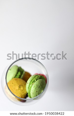many sweet tasty macaroon desserts of purple pink yellow and green color lie in a transparent glass. for splash screens labels flyers banners