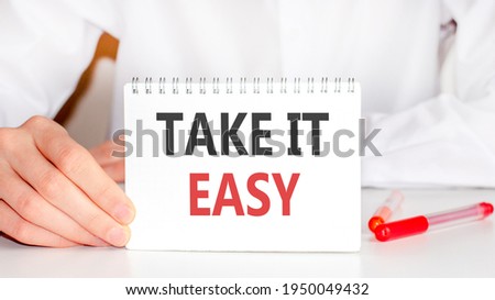 On the table there is a red marker and a white paper tablet on which the text is written - take it easy, red and black letters. Business concept.