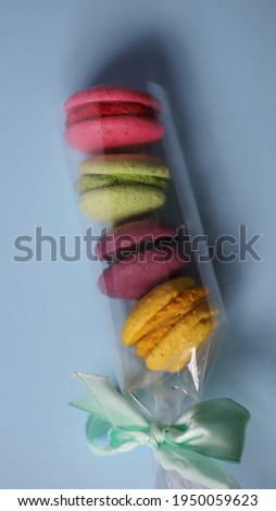four sweet tasty macaroon desserts in purple pink yellow and green lie on top of each other on a light background. for splash screens labels flyers banners