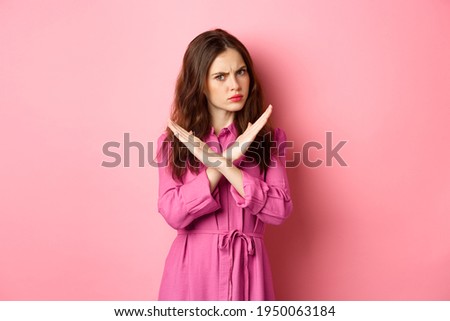 Displeased angry woman blocking offer, showing cross stop gesture, saying no and shaking head in negative reply, standing over pink background Royalty-Free Stock Photo #1950063184