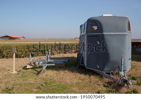A horse trailer with graphics is ready to hook up and go . silver horse trailer on green weadow . A trailer used for transporting one adult horse A trailer used for transporting one adult horse. Royalty-Free Stock Photo #1950070495