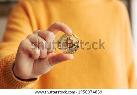 Woman showing a golden bitcoin in her hand. BTC and cryptocurrencies business in a digital decentralized finances concept