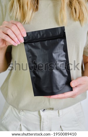 Kraft black paper packaging in a woman hands. Packaging for coffee, cosmetics. Packing closeup. Product for sale. Online shopping. Boxes with surprise. Delivery service, shipping. Empty, mockup