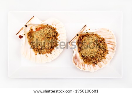 Backed scallops in shells on white background. Scallops au gratin on white plate top view. Mediterranean seafood. Fresh Shellfish. Aequipecten opercularis. Pecten Jacobaeus Royalty-Free Stock Photo #1950100681