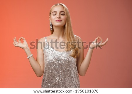 Keep calm party all night. Carefree unbothered happy charming stress-free blond young woman in stylish dress smiling relieved close eyes rejoicing standing lotus nirvana pose, breathing meditating