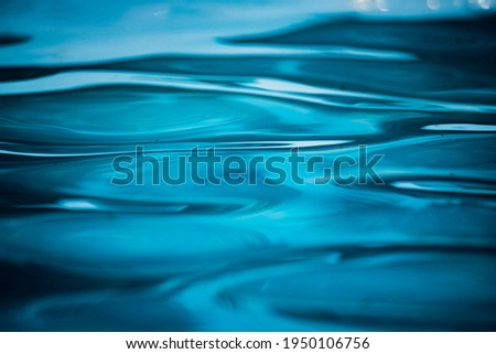 Blue water in the pool. Patterns and reflections and on the water surface. Splashing drops.