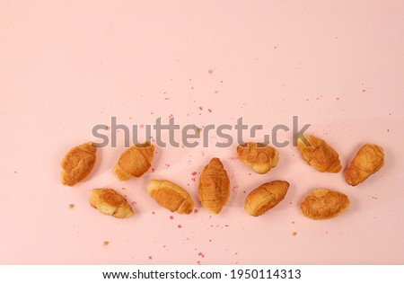 Fresh ruddy croissants on a light table with crumbs, top view, place for text. Modern bakery concept, business card for advertising or invitation. Delicious traditional breakfast, selective focus