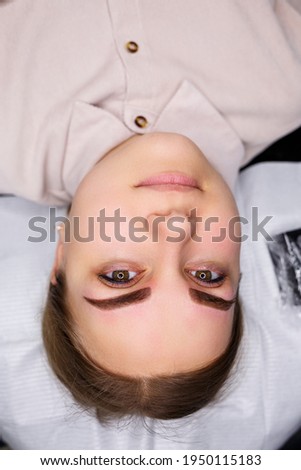 A close-up of the face of a young woman who has just had a permanent eyebrow tattoo done.