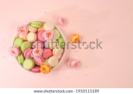 Fresh colorful macaroons in a gift box with flowers, top view. Modern bakery concept, business card for advertising or invitation. Delicious traditional breakfast, selective focus