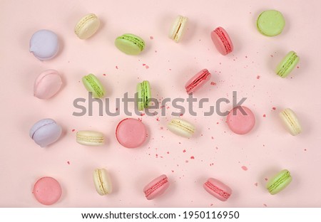 Fresh colorful macaroons on a light table with crumbs, top view. Modern bakery concept, business card for advertising or invitation. Delicious traditional breakfast, selective focus