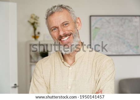 Smiling relaxed mature older bearded hipster man looking at camera. Happy handsome confident middle aged 50s male professional, standing at home office posing indoors for close up headshot portrait. Royalty-Free Stock Photo #1950141457