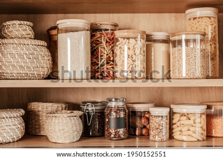 Organizing zero waste storage in kitchen. Pasta and cereals in reusable glass containers in kitchen shelf Royalty-Free Stock Photo #1950152551