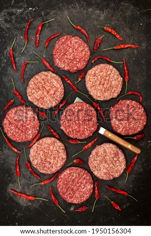 Raw Minced Steak Burgers from Beef and Pork Meat on Black Background, Overhead View. Uncooked Ground Meat Patties for Grilling. Burgers for BBQ Grill and Grilling Tools, Top View. Abstract Pattern.
