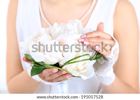 Bride holding wedding bouquet of white peonies, close-up