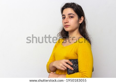 Woman with yellow t-shirt on white background with black wallet